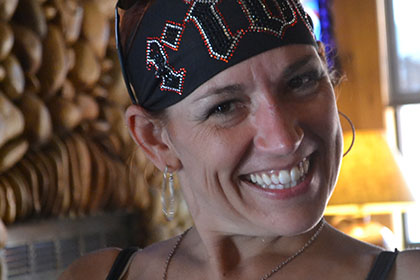 A woman wearing a bandana smiles for the camera.