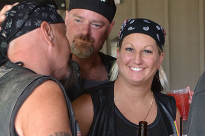 A woman next to a couple guys smiles at the camera.