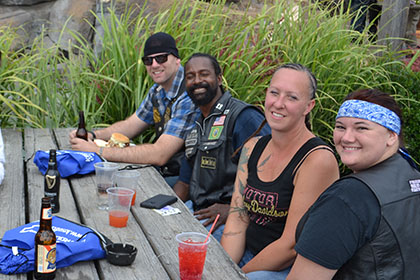 A group of people sitting at a wooden table outside.