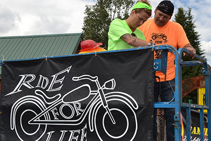 A Ride for Life committee member and volunteer setup a banner displaying the Ride for Life logo.