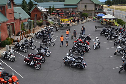 Rows of motorcycles with some people in the parking lot.