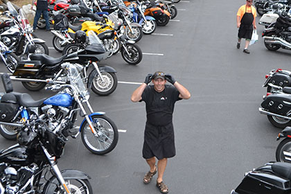 A few people and many motorcycles in the parking lot.