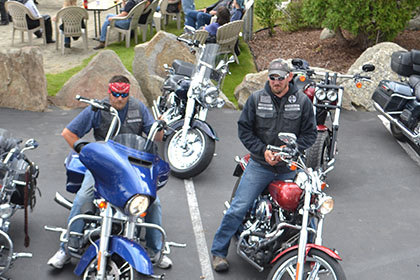 Couple guys sitting on their motorcycles in the parking lot.