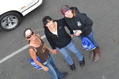 Three women standing in the parking lot.
