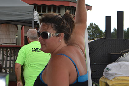 A woman standing under a tent next to the barbecue.