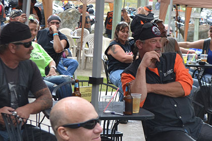 People sitting at tables outside, under tents at the event.