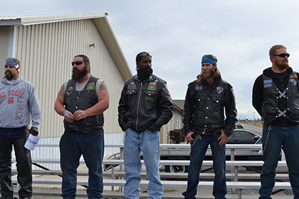 Five guys standing on bleachers.