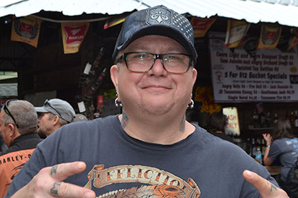 Man wearing glasses and a hat, smiles for the camera.