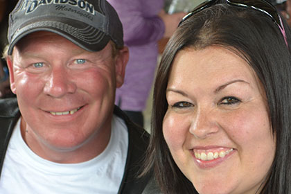 Man with Harley-Davidson hat and woman, smiling for camera.