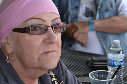 Woman wearing a pink bandana sitting at a table outside with a bearded man.