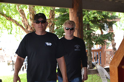 Two guys with dark sunglasses, walking toward the camera.