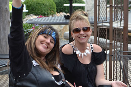 Women sitting outside, waving at camera.