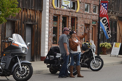 People standing next to their parked motorcycles.