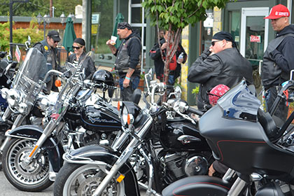 A line of parked motorcycles and some riders.