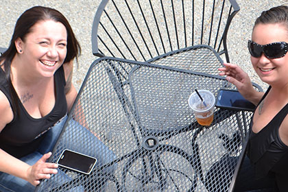 Two women sitting at a table outside.