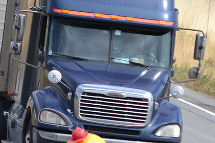 Person dressed as a Minion waves at a semi truck.